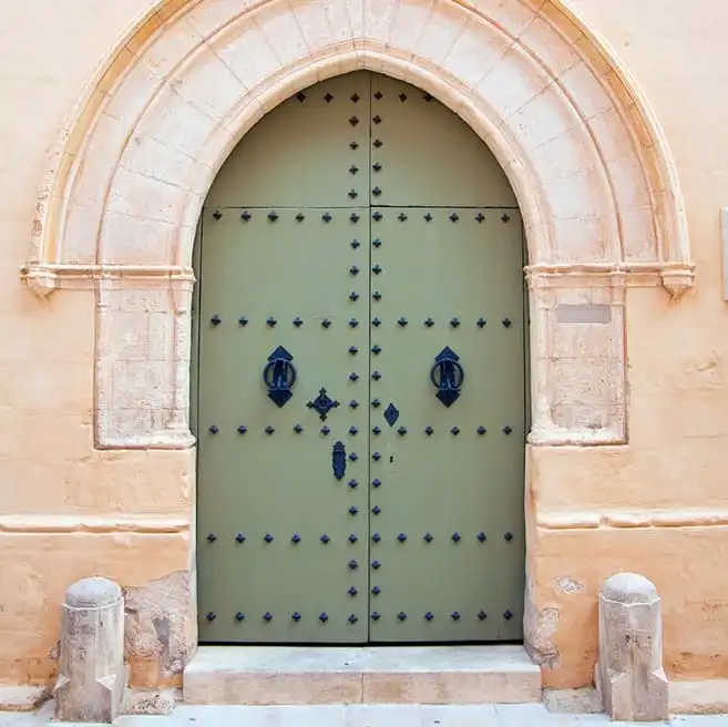 Puertas de portal Miguel A. del Barrio: puerta de portal verde con arco de piedra y herrajes tradicionales