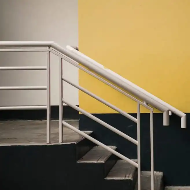 Miguel A. del Barrio: barandilla metálica blanca en escalera interior con pared amarilla